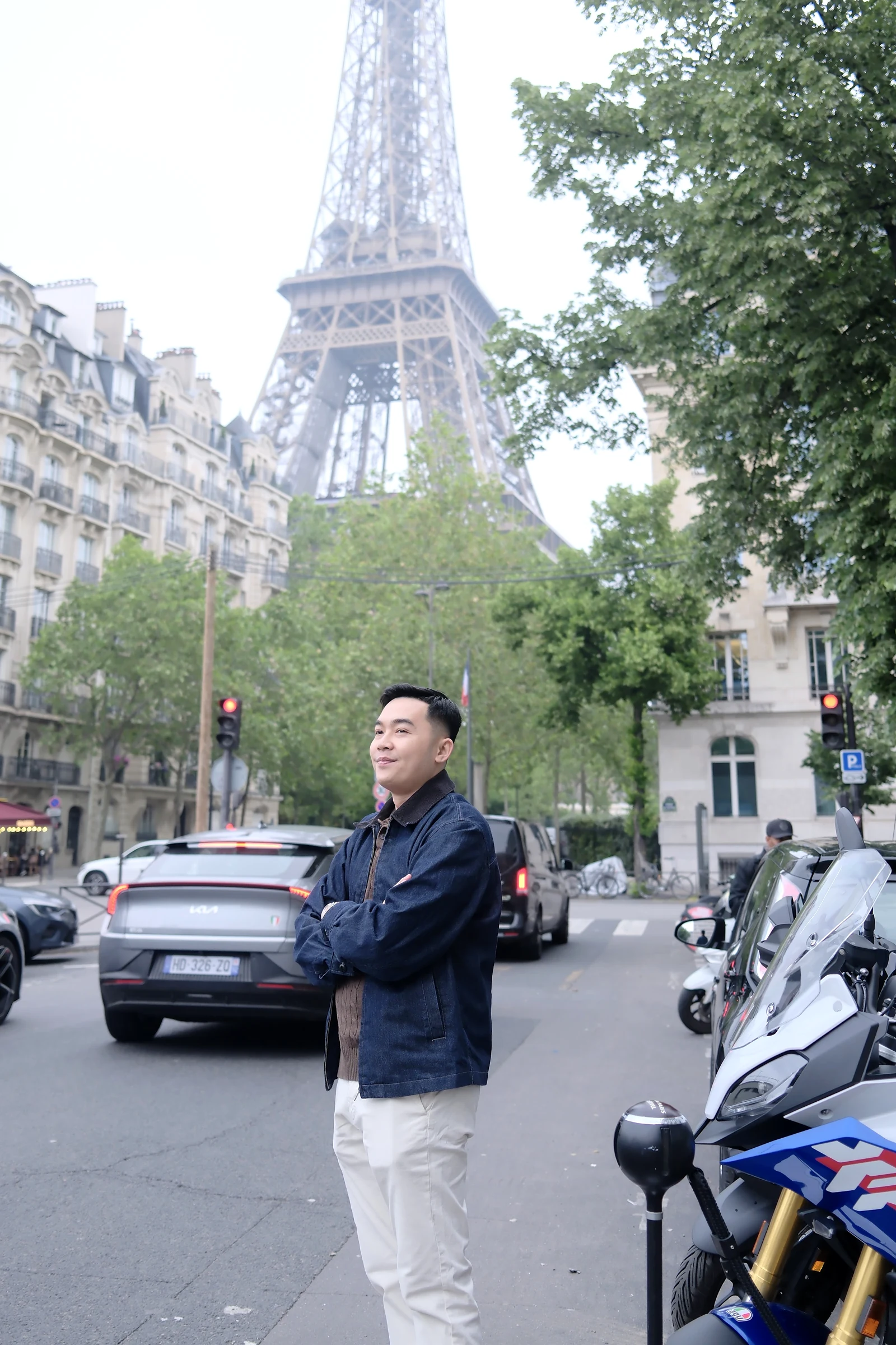 Nguyễn Bá Lục trên phố Paris với tháp Eiffel phía sau